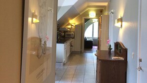 A hallway with a kitchen area in the background, a wooden bench, and a framed picture on the wall. - Eksjö Camping & Konferens - Hostel (Eksjo)