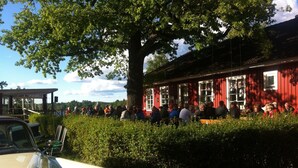 A red building with large windows and a group of people gathered outside. - Eksjö Camping & Konferens - Hostel (Eksjo)