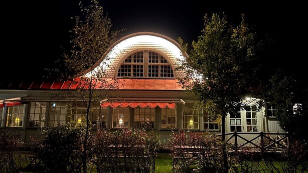 A building with a large arched entrance and a red roof, surrounded by trees and a fence. - Eksjö Camping & Konferens - Hostel (Eksjo)