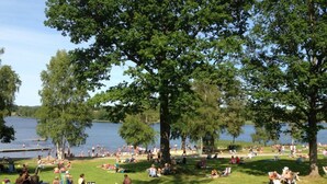A park with grassy areas, trees, and a lake. - Eksjö Camping & Konferens - Hostel (Eksjo)