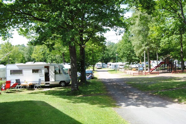 A campsite with RVs parked along a gravel path, surrounded by trees and a playground area. - Eksjö Camping & Konferens - Hostel (Eksjo)