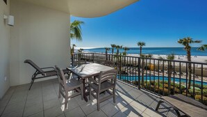 A balcony with a table and chairs, overlooking a beach and a pool. - Phoenix West 3BR! LOW FLOOR! (Orange Beach)