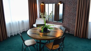 A hotel room with a brick wall, a round wooden table with chairs, a potted orchid, and a large mirror. - Hotel am Markt (Karlsruhe)