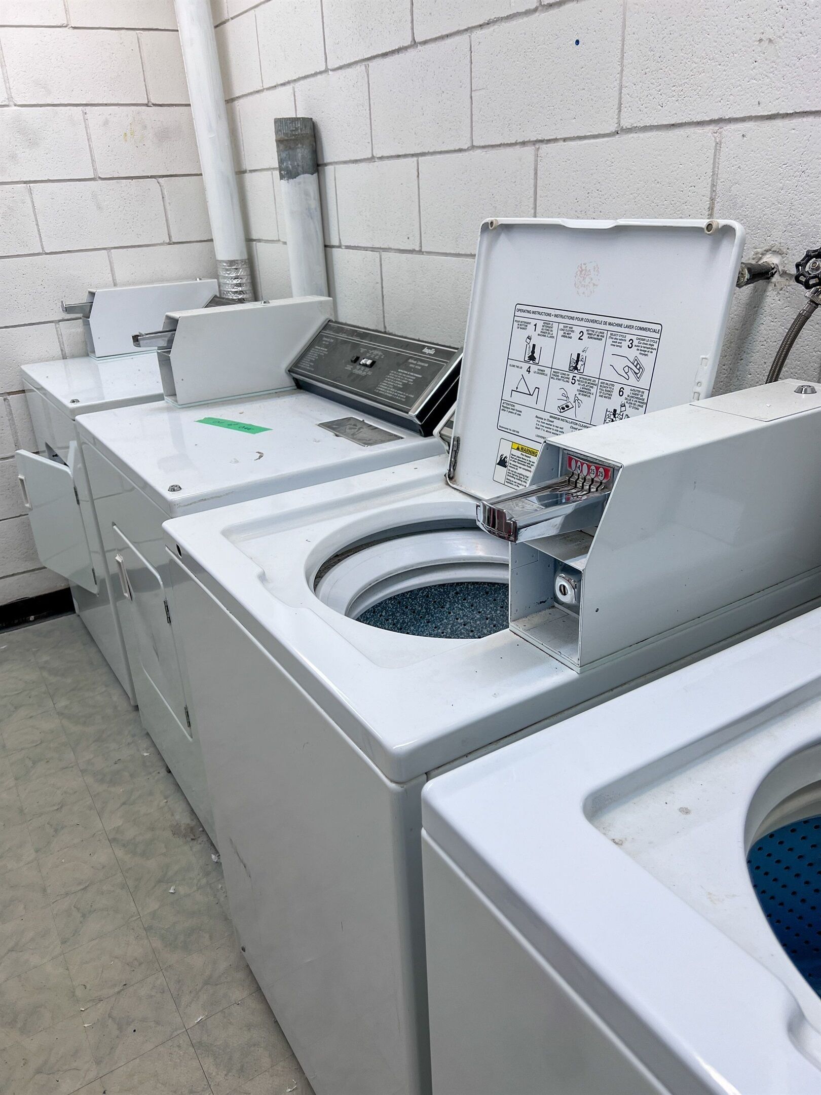 Une laverie équipée de plusieurs machines à laver et d’un panneau de commande.