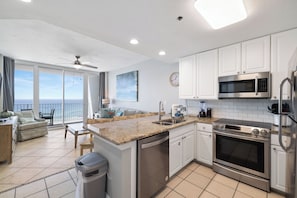A modern kitchen with white cabinets, stainless steel appliances, and a large island with a dishwasher.