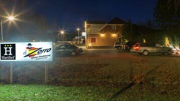 A parking lot with several cars and a building with illuminated signs.