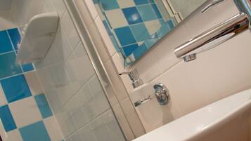 Un baño con lavamanos blanco, grifería cromada y baldosas blancas y azules a cuadros.