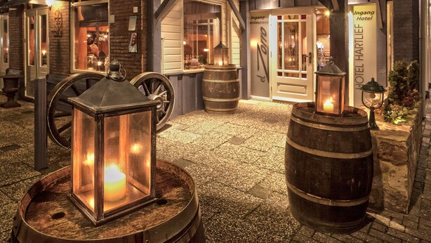 L’entrée d’un hôtel au décor rustique, agrémentée de tonneaux en bois et de lanternes.