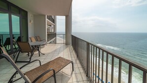 Un balcon avec vue sur l’océan, aménagé avec des chaises et une table.