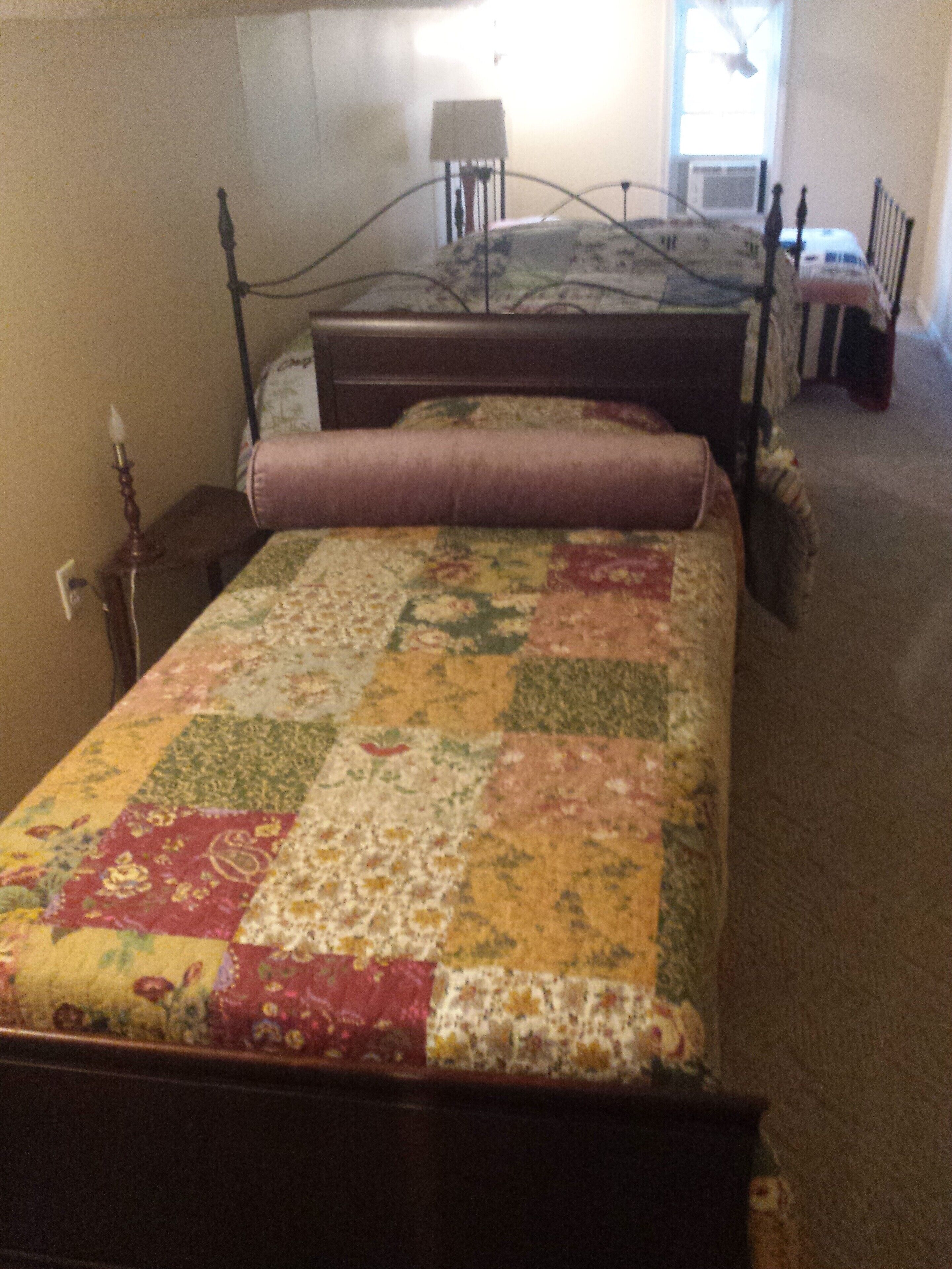 A bedroom with a bed, a nightstand, a lamp, and a window.