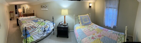 A bedroom with two beds, a nightstand, a lamp, a wall clock, and a 'Beach' sign.