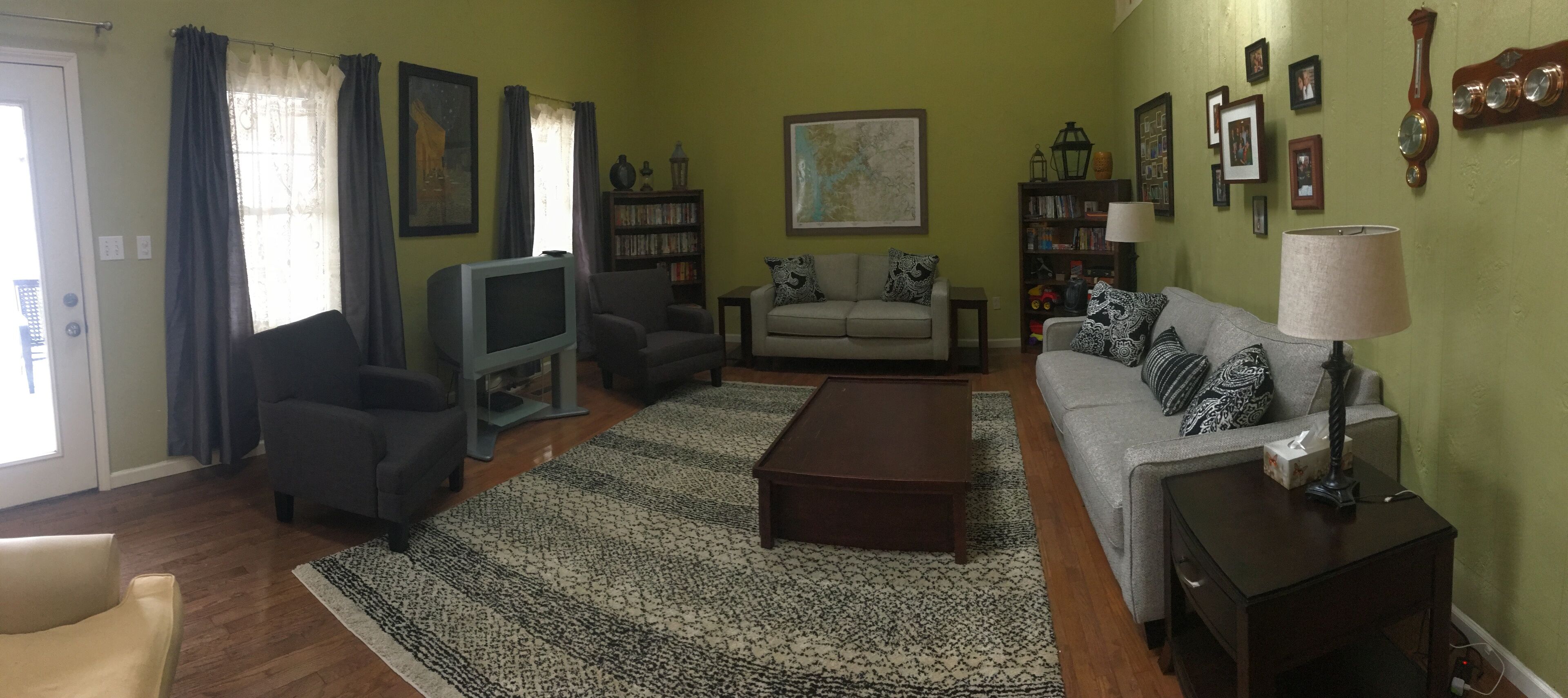 A living room with a sofa, armchairs, a coffee table, and a television.