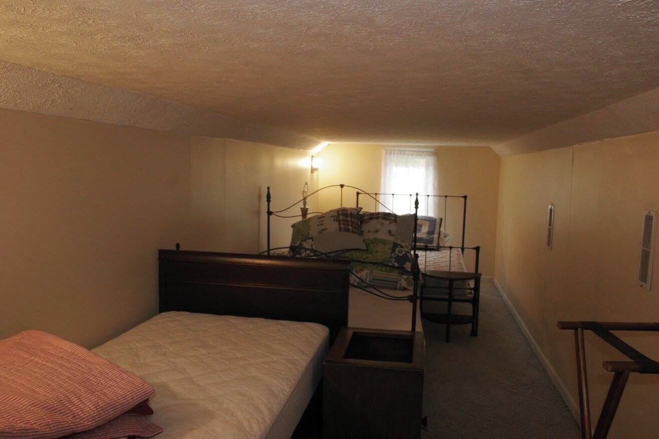 Une petite chambre à coucher peu éclairée, avec un lit simple, une chaise et un bureau.