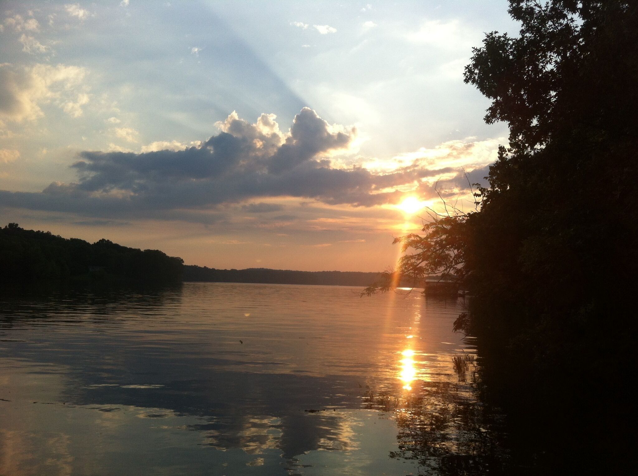 Un atardecer sobre un lago tranquilo con una orilla boscosa.