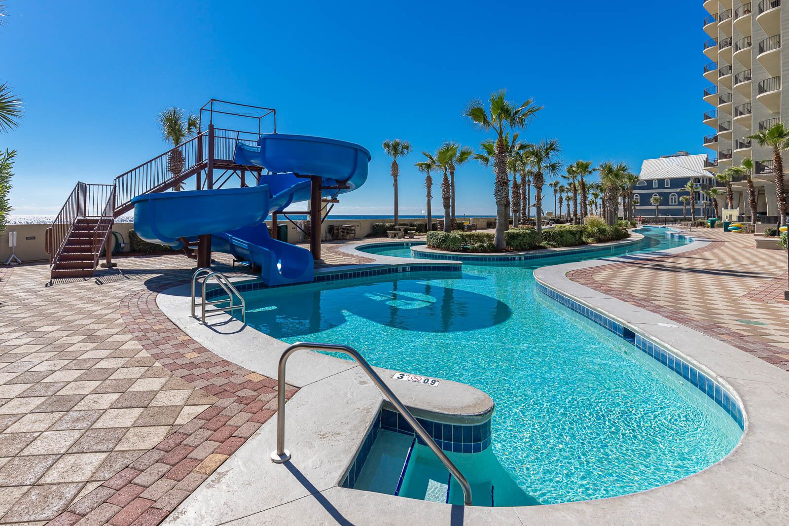 A pool area with a blue slide and a staircase leading to a deck.