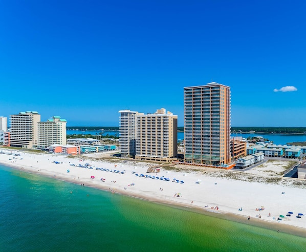 A coastal cityscape with high-rise buildings, a sandy beach, and a clear blue sky.
