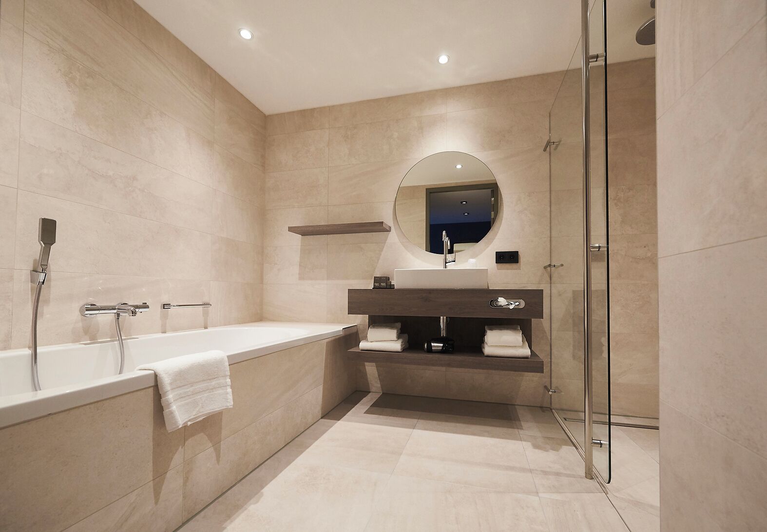 Ein modernes Badezimmer mit einer freistehenden Badewanne, einem Waschtisch mit Spiegel und einer Duschkabine aus Glas.