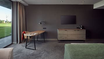 Een moderne hotelkamer met een groot raam, een eettafel, een groene bank en een houten kast.