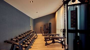 Une salle de sport équipée de matériel d’exercice, d’un banc et d’une machine fixée au mur.