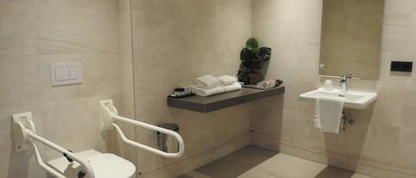 Un baño moderno con inodoro, barra de apoyo, lavamanos y espejo.