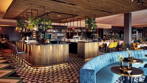 A modern bar area with a wooden ceiling, bar stools, and a seating area with round tables. - Van der Valk Hotel Leeuwarden (Leeuwarden)