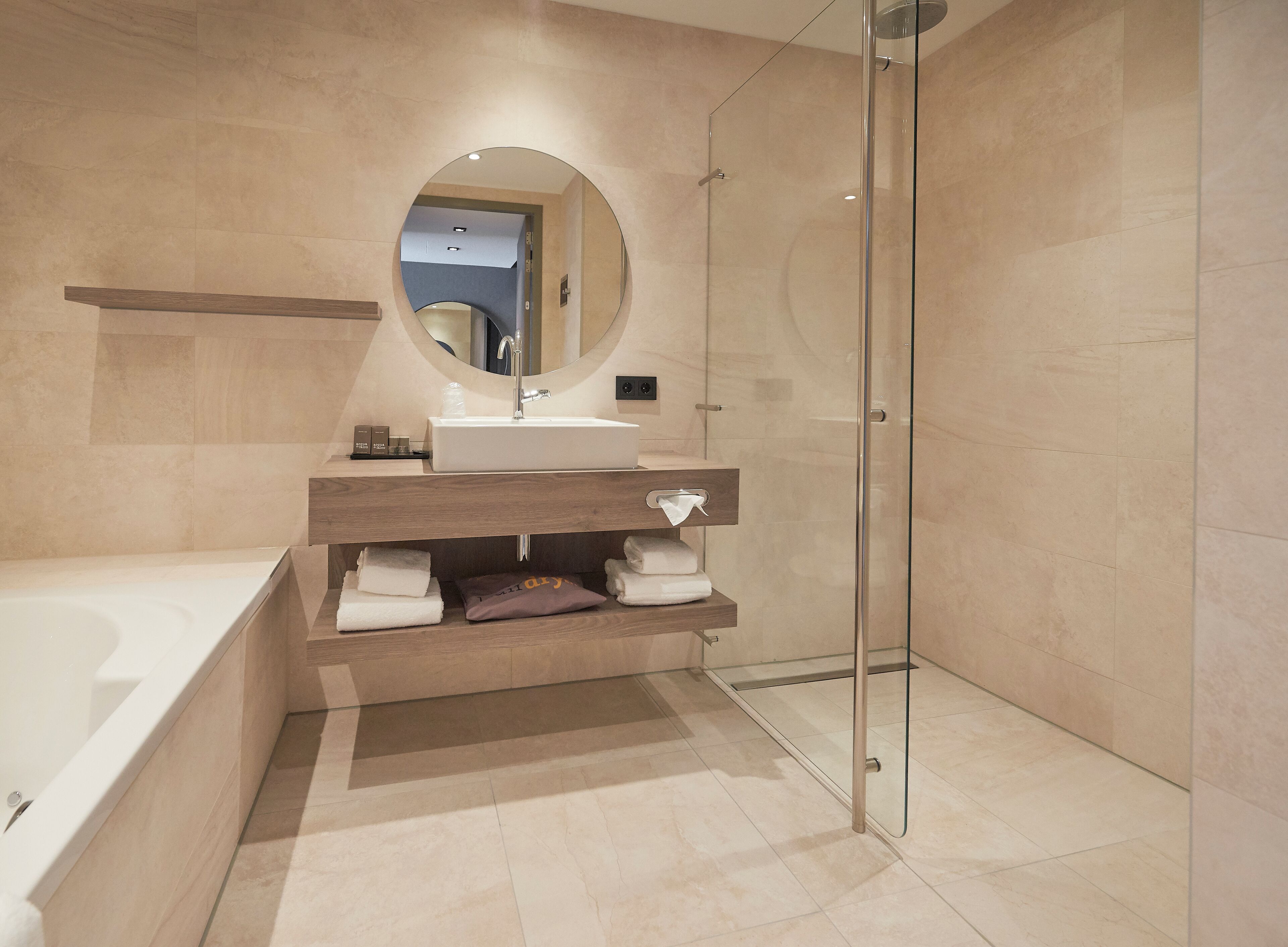 Un baño moderno con ducha de vidrio, lavamanos blanco y espejo integrado.