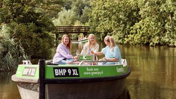 A boat with three people on board, a sign indicating a price of BHP 9 XL, and a website for booking.