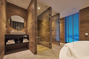 Un baño moderno con pared de madera, espejo redondo, lavabo blanco y mampara de vidrio.