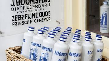 A poster advertising J. Boomsma's Distillerij Leeuwarden (Holland) with a photo of a man and a bottle of beer. In front, there are several bottles of Boomsma beer in a wicker basket.