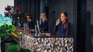 A reception desk with a stone-like textured wall, a laptop, and a telephone. - Van der Valk Hotel Leeuwarden (Leeuwarden)