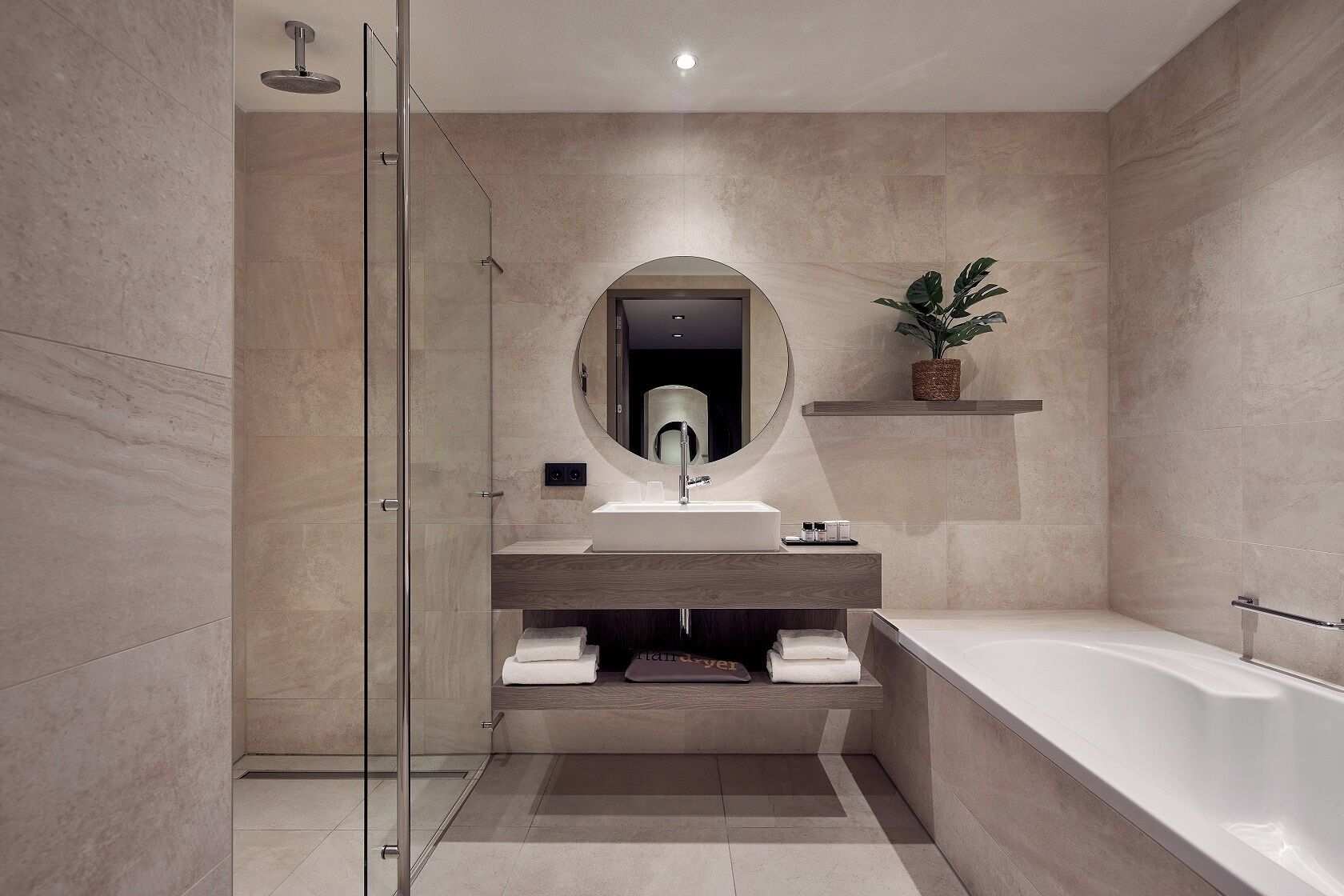 Une salle de bain moderne dotée d’une douche à parois de verre, d’un miroir rond, d’un lavabo intégré et d’une baignoire sur pieds.