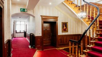 A grand staircase with wooden balusters and red carpeted steps leading to a landing.