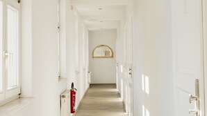 A long, narrow hallway with white walls and wooden flooring, leading to a door at the end. - Hotel und Restaurant Deutscher Kaiser (Perleberg)
