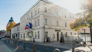 A historic building with a classic European architectural style, featuring a prominent entrance and a flag. - Hotel und Restaurant Deutscher Kaiser (Perleberg)