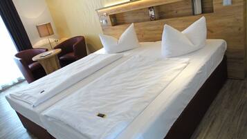 A hotel room with a large bed, a small desk, a chair, and a wooden headboard.