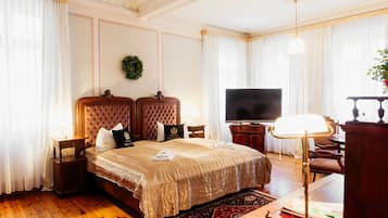 A hotel room with a large bed, a television, a desk, and a chair.
