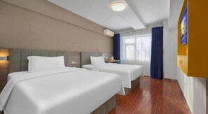 Habitación de hotel con dos camas, piso de madera, televisor de pantalla plana y ventana con cortinas.