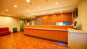 A reception area with a red sofa, a reception desk, and a television screen. - 7 Days Inn (Tianjin)
