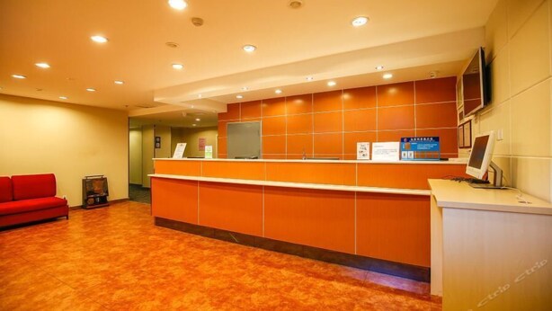 A reception area with a red sofa, a reception desk, and a television screen. - 7 Days Inn (Tianjin)