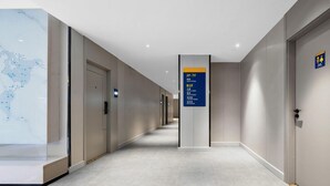 A modern hotel corridor with a digital world map display, directional signs, and a clean, minimalist design. - 7 Days Inn (Tianjin)