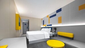 A modern hotel room with a bed, a seating area with a yellow bench, a small round table, and a wall with geometric patterns. - 7 Days Inn (Tianjin)