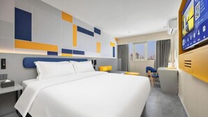 A modern hotel room with a large bed, a desk, a chair, and a TV. - 7 Days Inn (Tianjin)