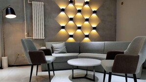 A modern living room with a grey sofa, two armchairs, a small round table, and a floor lamp. - 7 Days Inn (Tianjin)