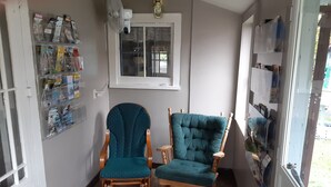 Une pièce avec deux chaises en bois, une fenêtre et un ventilateur fixé au mur.