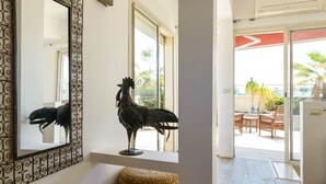 Una habitación con un espejo grande y ornamentado, una estatua decorativa de gallo y una cesta tejida.