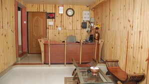 Una habitación con paneles de madera, una recepción, una mesa de vidrio y sillas de madera tradicionales.