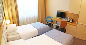 A hotel room with two beds, a desk with a TV, a chair, and a small kitchenette. - Europa (Kaliningrad)