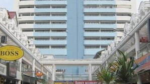 A tall, multi-story building with a central blue stripe, surrounded by shops and a sign that reads "BOSS".