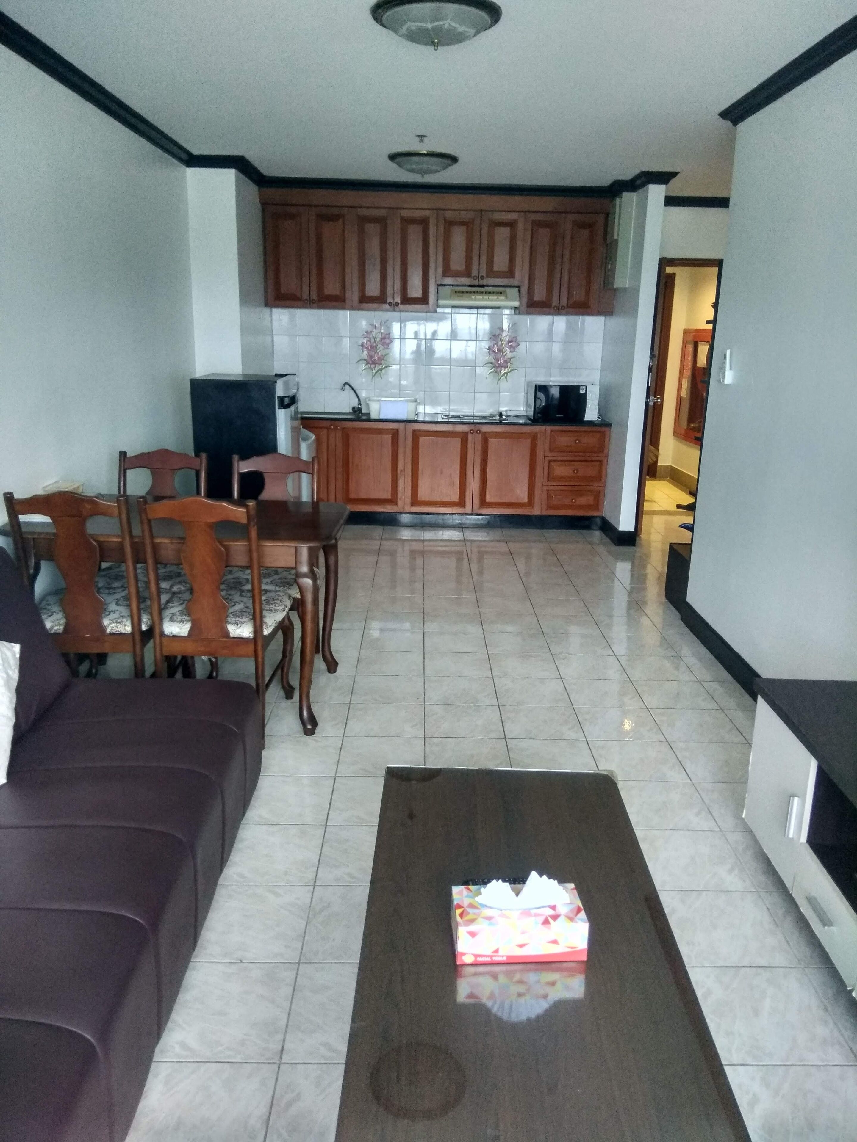 A living room with a brown sofa, a coffee table with a box, and a dining area with wooden chairs and a table.