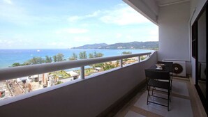 A balcony with a view of the sea and a distant mountain range.